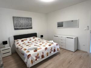 een witte slaapkamer met een bed en een dressoir bij Apartments Puntamika in Zadar