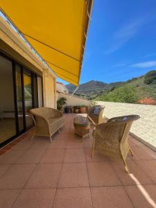 a patio with wicker chairs and a yellow umbrella at Appartement 2 chambres - 4 personnes 4HD47 in Collioure