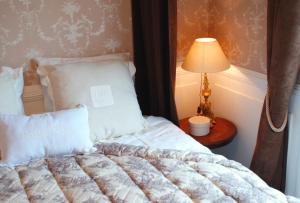 a bed in a room with a lamp on a table at La Gougeonnais in La Richardais