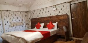 a bedroom with a bed with red pillows at Satpura Resort in Pachmarhī