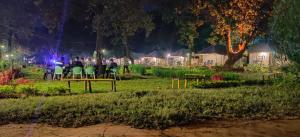 a group of people sitting on a picnic table at night at Satpura Resort in Pachmarhī