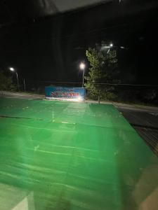 - un court de tennis vert avec un panneau la nuit dans l'établissement Nhà nghỉ Sunmi, à Cần Thơ