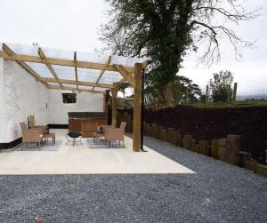 a wooden pergola with chairs and a table at Dundrine Cottage in Maghera