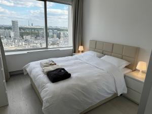 a bedroom with a white bed with a large window at Paris Bleu in Puteaux