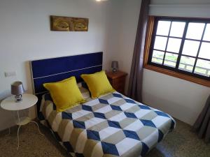Un dormitorio con una cama con almohadas amarillas y una ventana en Los atardeceres más bellos del Sauzal, en Sauzal