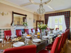 a dining room with a long table and red chairs at Ludbrook Manor in Ivybridge