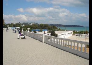 a woman sitting on a bench on a bridge over a beach at The Arabesque House in La Marsa