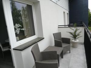 einen Balkon mit Stühlen, einem Fenster und einer Pflanze in der Unterkunft Manhattan in Bielawa