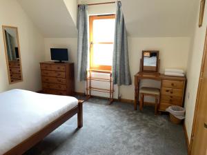 a bedroom with a bed and a desk and a window at Nevis Croft Apartment 3 in Fort William
