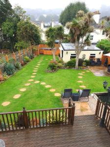 a backyard with a lawn with chairs and trees at Appletorre House Holiday Flats in Torquay