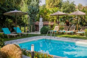 una piscina en un patio con sillas y sombrillas en Artemis Goddess Nest - Aquatic Getaway en Evkarpía