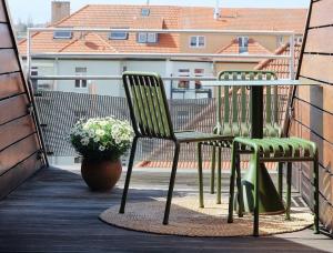 un balcón con 2 sillas, una mesa y un jarrón de flores en Design Apartments "Hier war Goethe nie", en Weimar