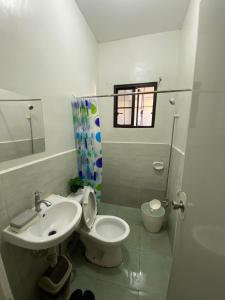 a white bathroom with a toilet and a sink at Radex Place Staycation , 2BR, 6 PAX in Mati