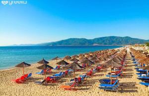 un mucchio di sedie e ombrelloni su una spiaggia di Artemis Goddess Nest - Aquatic Getaway a Evkarpía