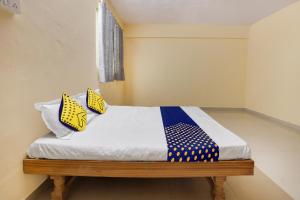 a bed with yellow and blue pillows on it at SPOT ON Hotel Shubham in Aurangabad