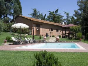 a pool in front of a house with chairs and an umbrella at Villa Camelia in Cortona
