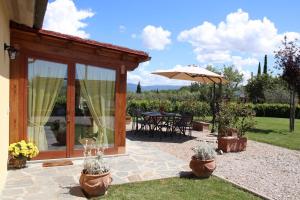 un patio con mesa y sombrilla en Villa Mira, en Cortona