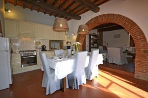a kitchen with a table with white chairs and an archway at Casa I Pini in Cortona