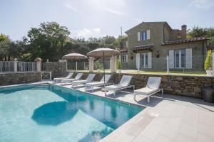 a swimming pool with chairs and umbrellas next to a house at Villa Chiara in Cortona
