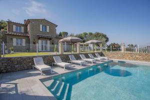 a pool with chairs and umbrellas in front of a house at Villa Chiara in Cortona