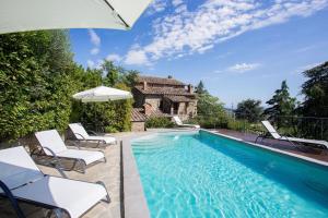 a pool with chairs and an umbrella next to a house at Villa I Cocciai in Cortona