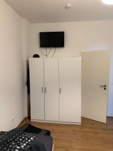 蓋爾森基興的住宿－Domum 2 Moderne Ferien- Monteurapartments inkl Wlan und Waschmaschine in Gelsenkirchen，卧室配有白色橱柜和平面电视。