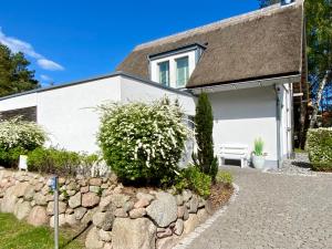 een wit huis met een stenen muur en een bank bij Ferienhaus am Lotsenstieg 6 in Ostseebad Karlshagen