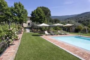 a swimming pool in a yard with chairs and umbrellas at VILLA SAN PIETRO in Cortona