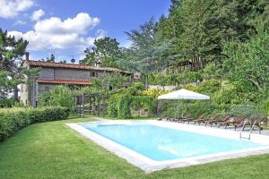 a swimming pool in a yard with chairs and an umbrella at Villa Magnolia in Cortona