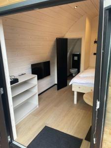 Habitación pequeña con cama y TV. en Boslodges Veluwe en Nunspeet