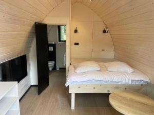 Bett in einem kleinen Zimmer mit einem TV in der Unterkunft Boslodges Veluwe in Nunspeet