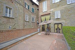 a patio with an umbrella in front of a brick building at Appartamento Passerini in Cortona