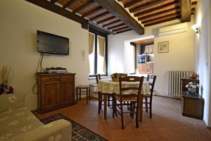 sala de estar con mesa, sillas y TV en Appartamento Passerini, en Cortona