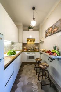 een keuken met witte kasten, een wastafel en 2 krukken bij Casa San Michelangelo in Cortona