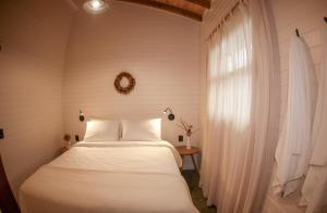 a bedroom with a white bed and a window at Skyline Urubici - Barn in Urubici