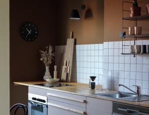 eine Küche mit einem Waschbecken und einer Uhr an der Wand in der Unterkunft Design Apartments "Hier war Goethe nie" in Weimar
