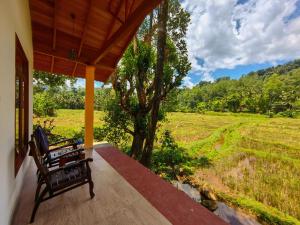a porch with a bench and a view of a field at Traveller's Choice Sinharaja in Deniyaya