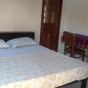 ein Schlafzimmer mit einem Bett, einem Stuhl und einer Tür in der Unterkunft Bali Traditional homestay in Gianyar