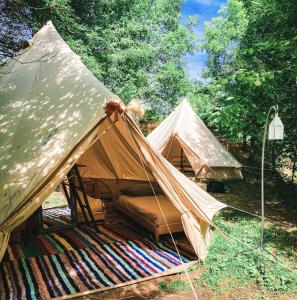 a tent with a bed in the middle of a forest at Kârma Hôtel in Saint-Genis-les-Ollières