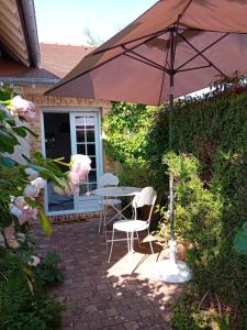 eine Terrasse mit einem Tisch, Stühlen und einem Sonnenschirm in der Unterkunft Chambre d hotes de charme in Vernon