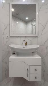 Baño blanco con lavabo y espejo en One-bedroom apartments in Tbilisi Gardens, en Tiflis