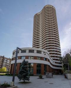un edificio alto con un árbol delante de él en One-bedroom apartments in Tbilisi Gardens, en Tiflis