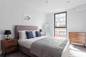 um quarto com uma cama com almofadas azuis e uma janela em Modern & Spacious Apartment In Central Birmingham em Birmingham