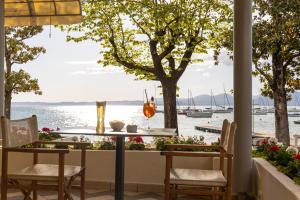 - une table et des chaises sur une terrasse avec vue sur l'eau dans l'établissement Hotel Nettuno, à Bardolino