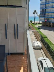 un balcon avec des portes blanches et une voiture garée dans la rue dans l'établissement Haro Beach San Juan, à El Campello