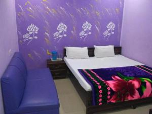 ein lila Schlafzimmer mit einem Bett und einem lila Sofa in der Unterkunft Hotel Atithi Galaxy Kanpur Near Railway Station Kanpur - Wonderfull Stay with Family in Kānpur