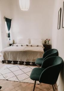 a bedroom with a bed and two green chairs at NOSADE Venue in Marrakesh