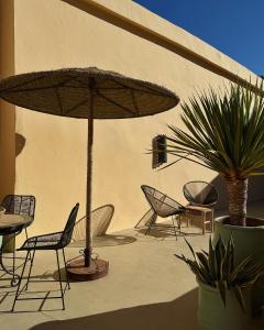 a patio with chairs and an umbrella and plants at NOSADE Venue in Marrakesh