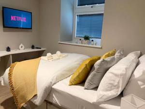 una camera da letto con un letto bianco con cuscini gialli di HNFC Stays - Prime Central Newcastle Studio w/ Gym+Free parking a Newcastle upon Tyne