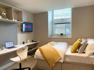 a bedroom with a bed and a desk with a laptop at HNFC Stays - Prime Central Newcastle Studio w/ Gym+Free parking in Newcastle upon Tyne